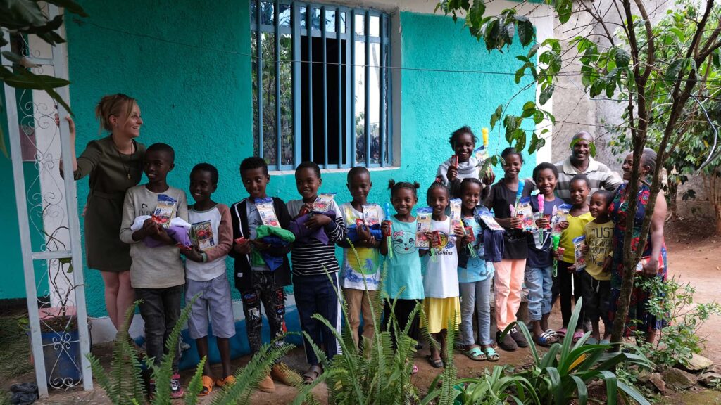 schoolkids standing in a line holding up their school supplies