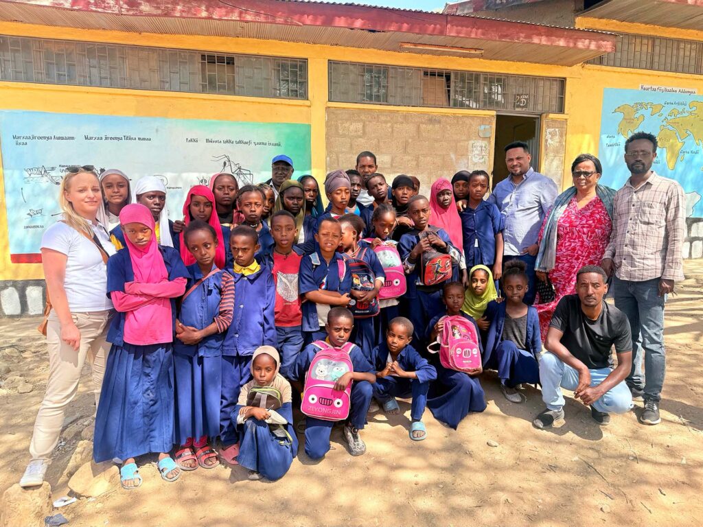 Tirza and Bruk are standing with about a couple dozen Ethiopian school kids